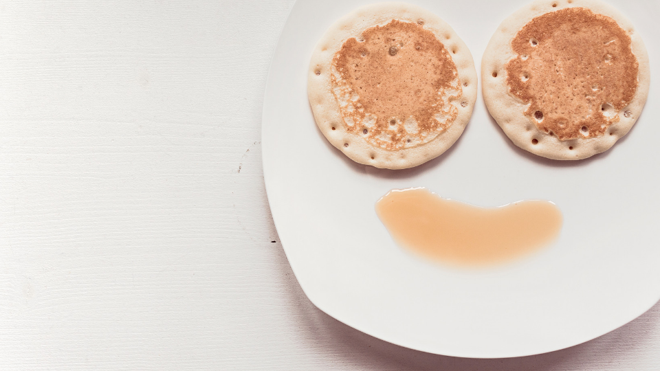two pancakes laid out as eyes with syrup to look like smile
