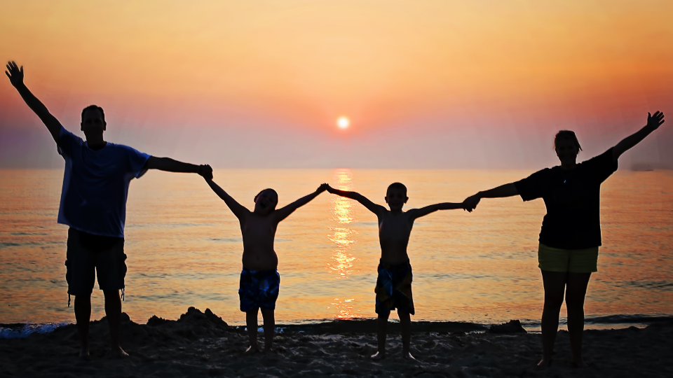 family holding hand on the beach in silhouette
