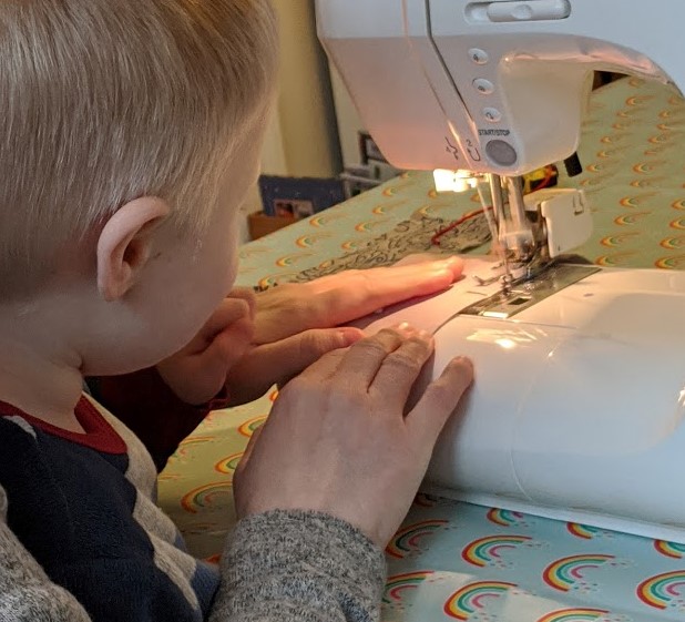 child at sewing machine with mother